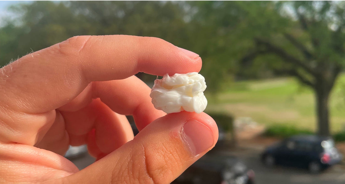 Fingers holding a large white Chios mastic tear outdoors