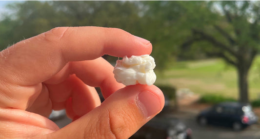 Fingers holding a large white Chios mastic tear outdoors