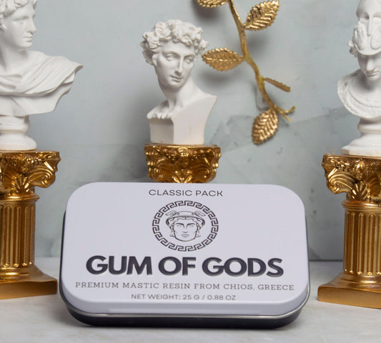 Gum of Gods Classic Pack tin in front of white Greek statues and gold columns