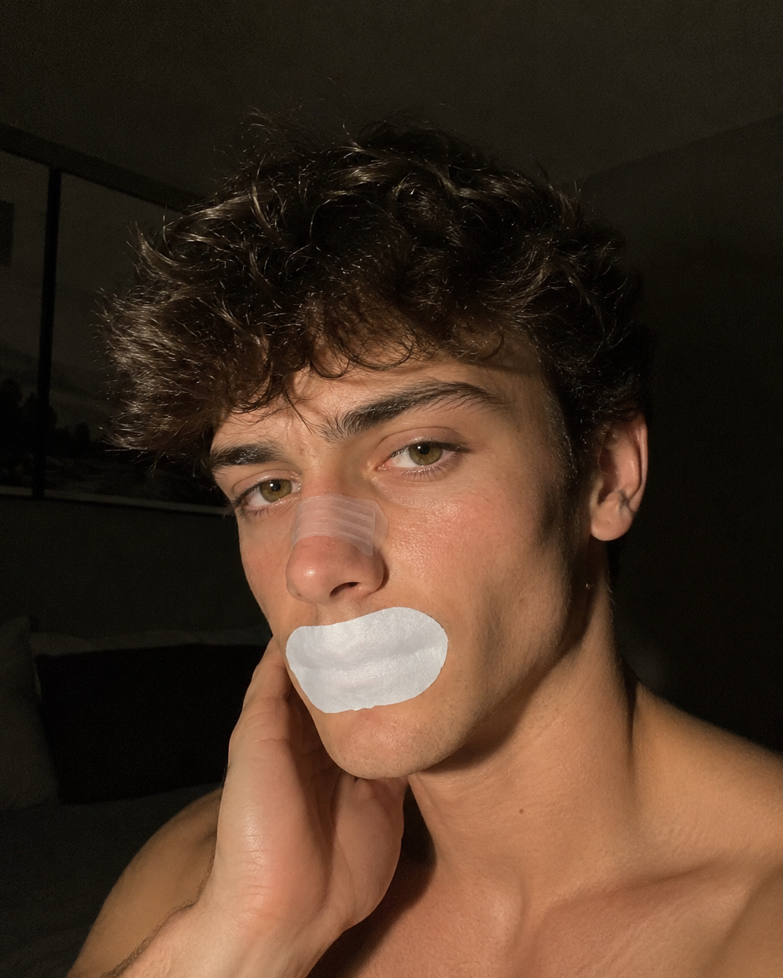 Real customer portrait wearing a white mouth tape strip at night.